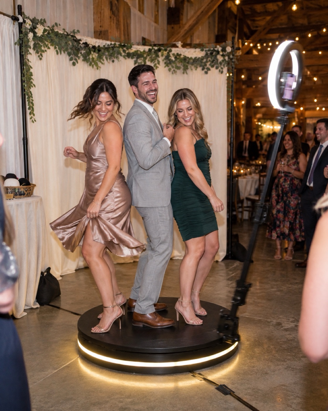 Three guests dancing on the 360 video booth platform at a reception